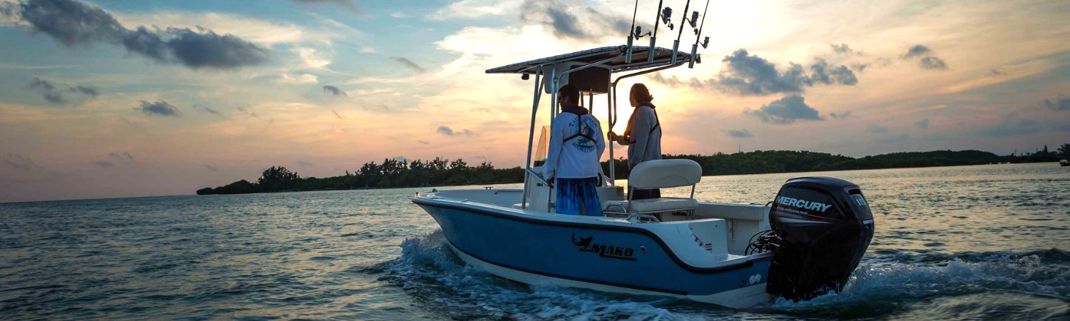 Two individuals riding a Mercury Marine® boat into the sunset on ocean waters